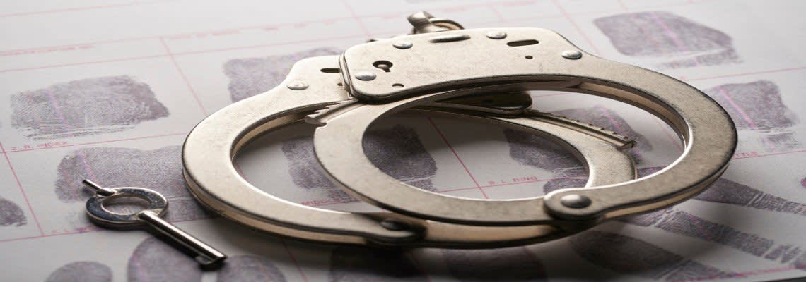 Handcuffs with a key on top of fingerprints