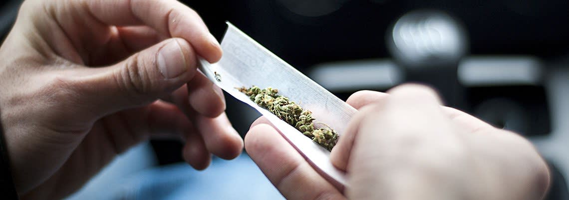 Man rolling a joint in a car