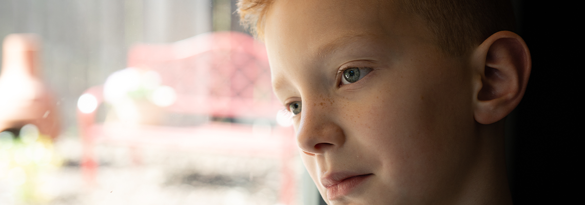 Red Head Caucasian Child Sad Looking Out a Window from Kitchen