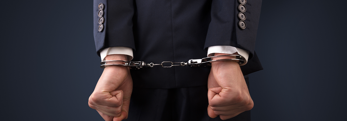 Person in business suit with hands in handcuffs