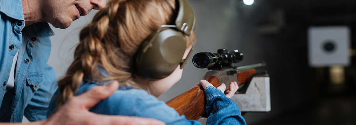 Man helping his daughter shoot gun.