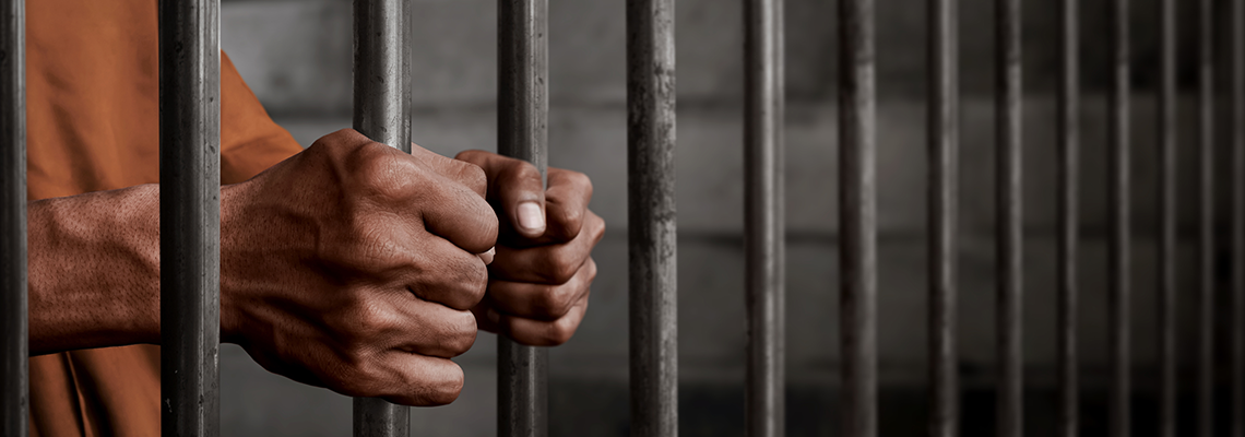 Man Holding Steel Bars of his Prison Cell