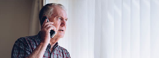 Older Man Looking Out WIndow Holding Phone